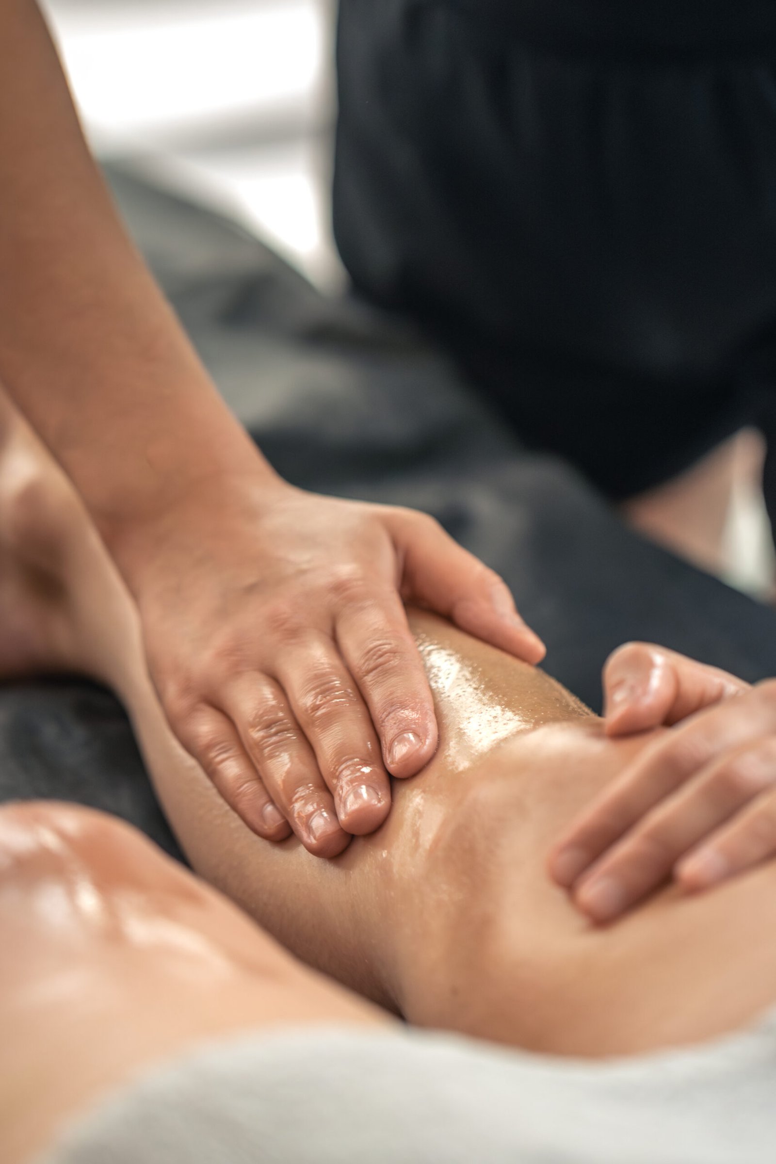 Masaje corporal en piernas con aceite durante una sesión en Ibiza